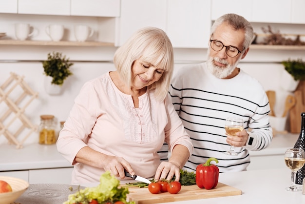 Cuisiner le dîner en famille ensemble. Sourire charmant couple de personnes âgées debout dans la cuisine et préparer le dîner tout en exprimant le bonheur et les soins