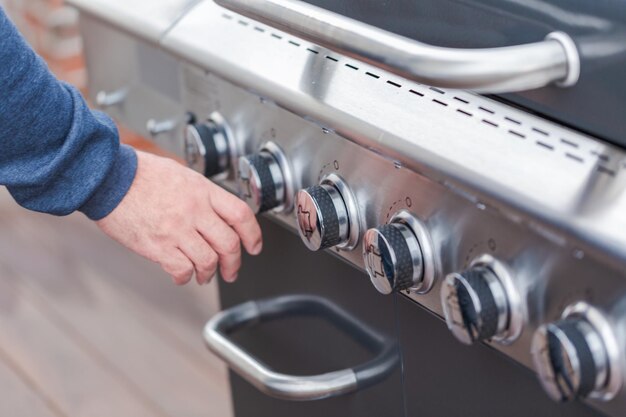 Cuisiner des hamburgers classiques sur un gril à gaz extérieur en été.