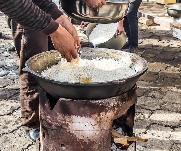 Cuisiner le pilaf, plat national asiatique au riz, dans un pot en métal à l'extérieur