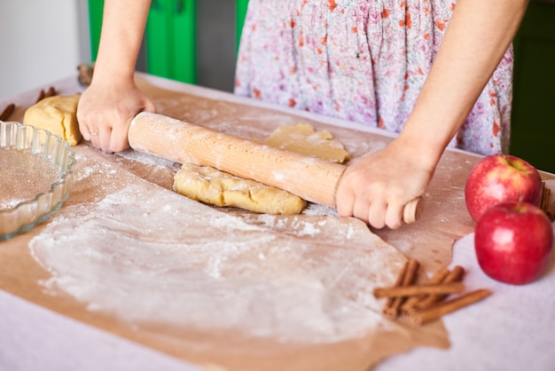 Cuisinez à la maison. Femme pétrir la pâte pour la tarte aux pommes sur la table de la cuisine. Style rustique