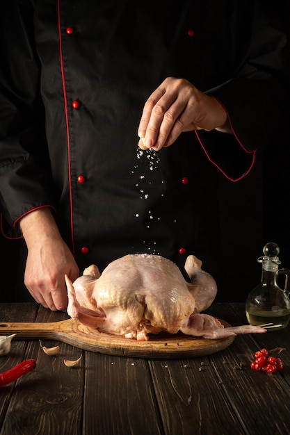 Le cuisinier ajoute du sel au poulet avant de rôtir