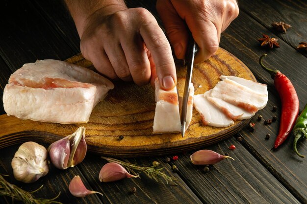 Photo un cuisinier coupe du lard sur une planche de cuisine avant de préparer un délicieux apéritif à l'ail.