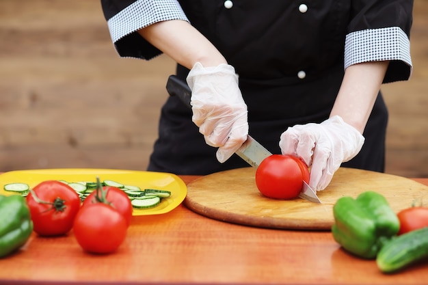 Le cuisinier coupe des légumes frais de la ferme pour le dîner sur la table