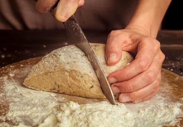 Le cuisinier coupe la pâte crue