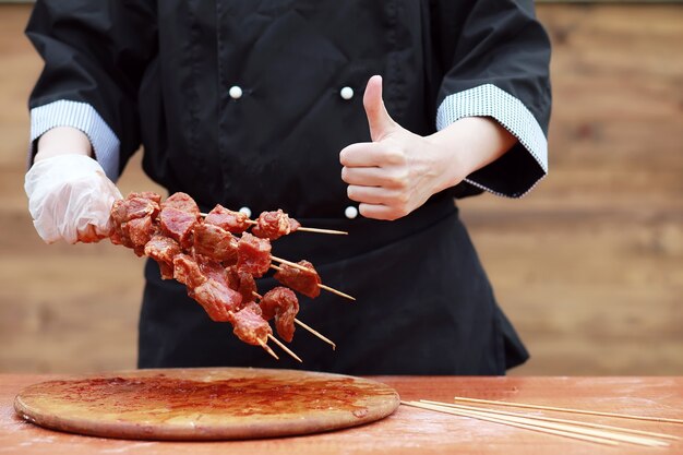 Le cuisinier coupe la viande pour la cuisson du barbecue sur la table