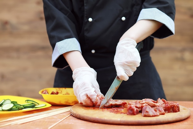 Le cuisinier coupe la viande pour la cuisson du barbecue sur la table