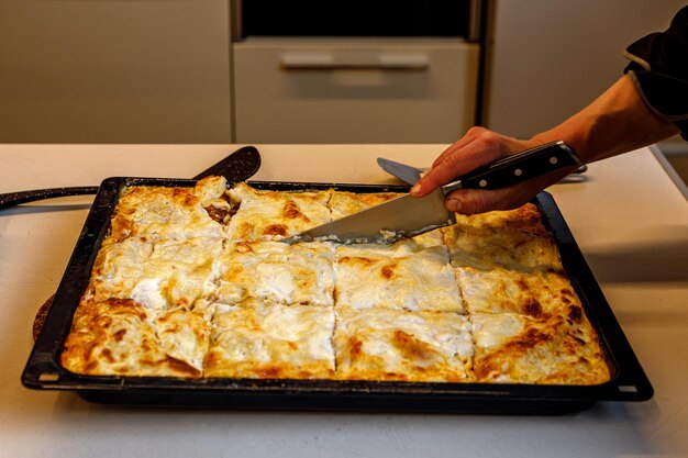 Le cuisinier coupe la vue latérale de la lasagne fraîche