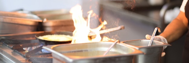 Le cuisinier fait cuire sur le fourneau avec un feu ouvert