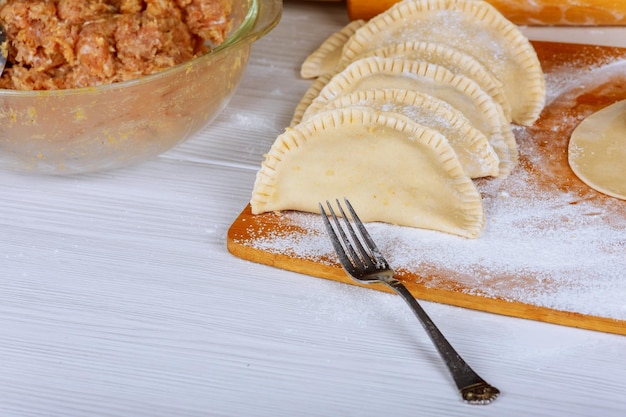 Le cuisinier fait du cheburek avec de la viande rôtie du chebure avec de la farine sur une planche de bois