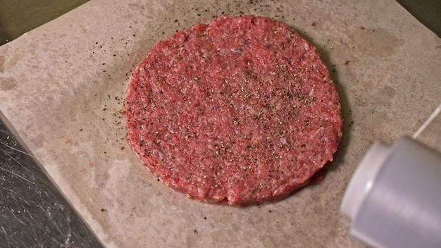 Le cuisinier fait des médaillons de viande pour les hamburgers Le chef en gants de cuisine noirs fait des escalopes Les escalopes sont nivelées dans un anneau en acier dans un médaillon uniforme