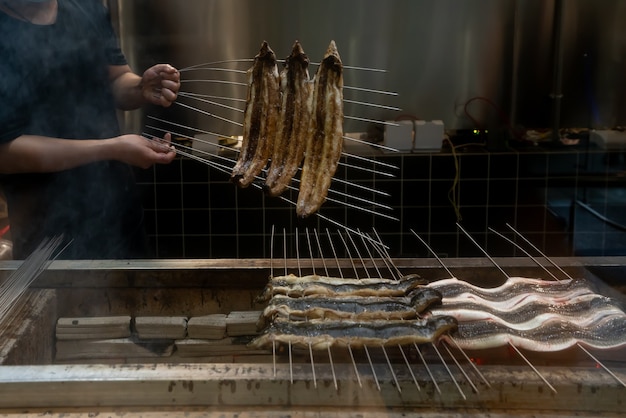 Le cuisinier fait rôtir des anguilles