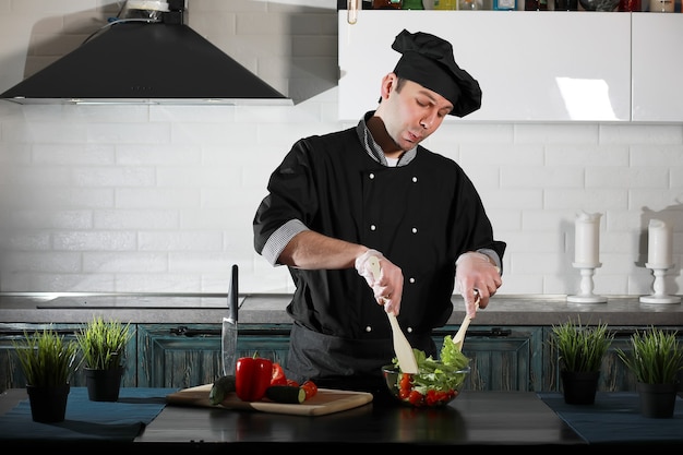 Cuisinier d'homme préparant la nourriture à la table de cuisine des légumes