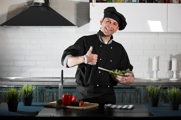 Cuisinier d'homme préparant la nourriture à la table de cuisine des légumes