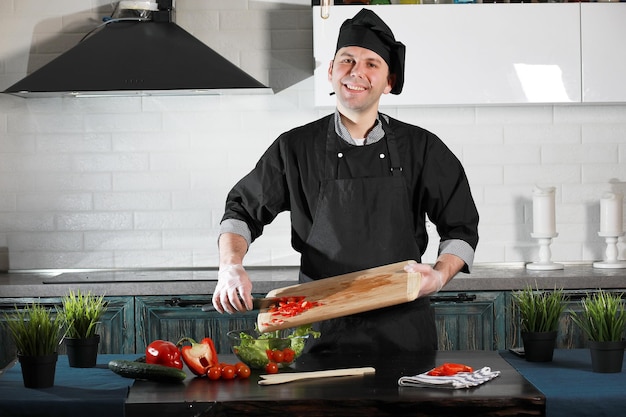 Cuisinier d'homme préparant la nourriture à la table de cuisine des légumes