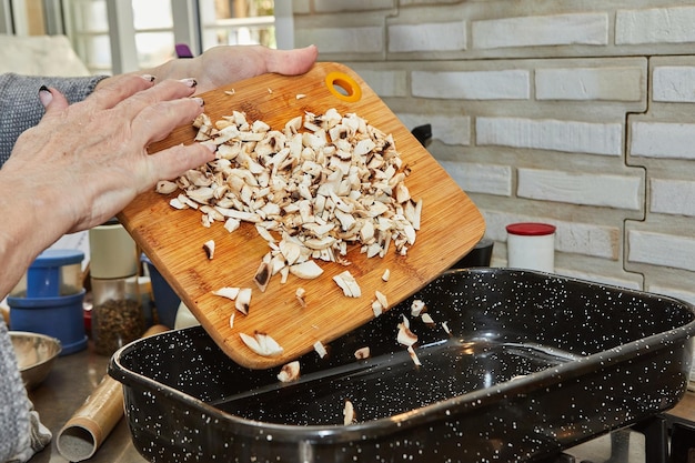 Le cuisinier jette des champignons dans une poêle carrée