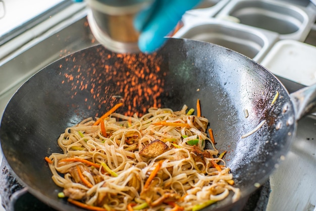 Le cuisinier prépare des nouilles de riz pour wok Street food