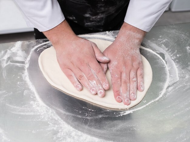 Cuisinier professionnel préparant la pâte à pétrir pour la cuisson. Des mains habiles pour préparer des plats savoureux