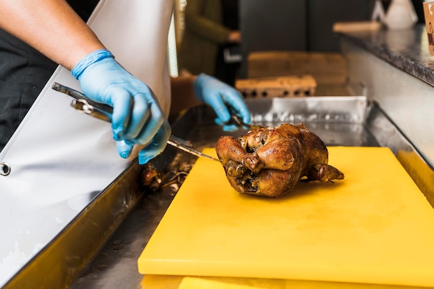 Photo cuisinier se préparant à découper un poulet qui a été grillé pour un client
