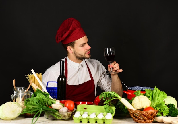 Le cuisinier ou le sommelier tient un verre de vin près de la table