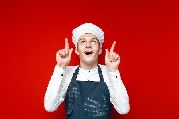 Cuisinier surpris regarde copyspace sur fond rouge isolé mec en uniforme de chef