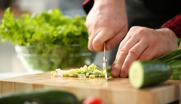 Le cuisinier tient un couteau à la main et coupe.