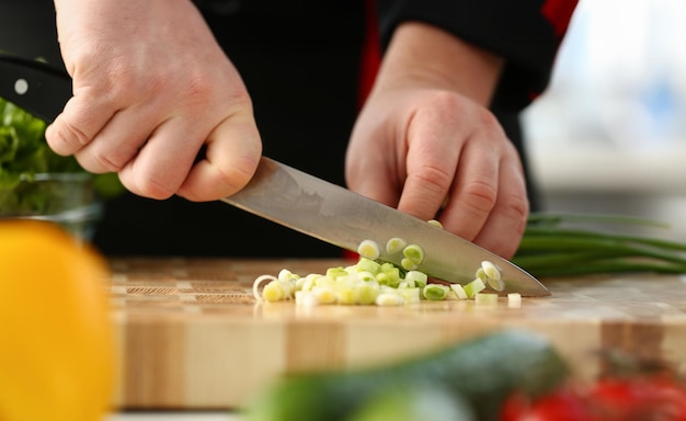 Le cuisinier tient un couteau à la main et coupe.