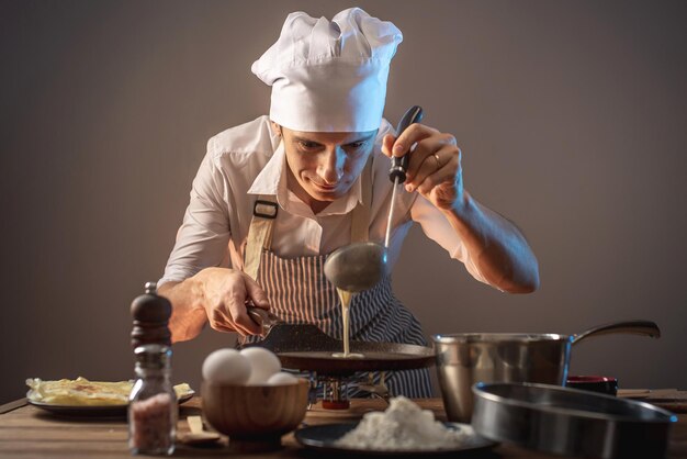 Un cuisinier verse de la pâte dans une poêle à frire chaude et cuit des crêpes faites maison