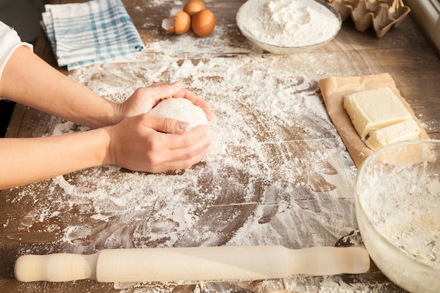 La cuisinière fait de la pâte. Avec tous les ingrédients sur la table. Vue de côté.