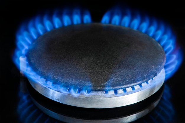 Cuisinière à gaz sur un fond noir fragment d'une cuisinière à gaz avec une flamme bleue cri d'énergie gros plan