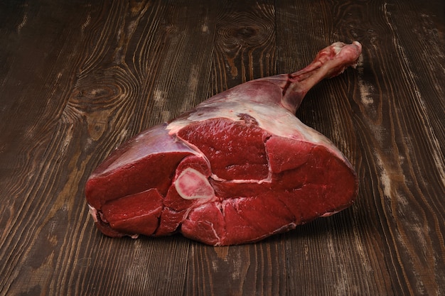 Cuisse de boeuf jeune frais cru sur fond de bois