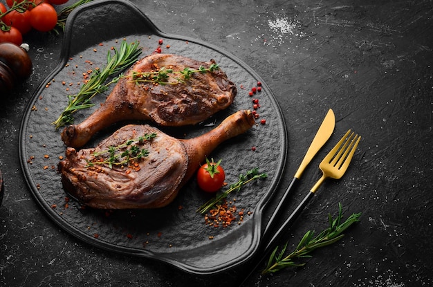 Cuisse de canard au four aux épices et romarin. Viande grillée. Vue de dessus. Vue de dessus à plat sur la table de coupe en pierre noire.