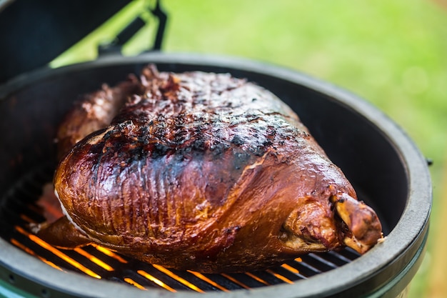 Cuisse de porc grillée et fumée sur un grill professionnel Griller du jambon de Prague dans le jardin