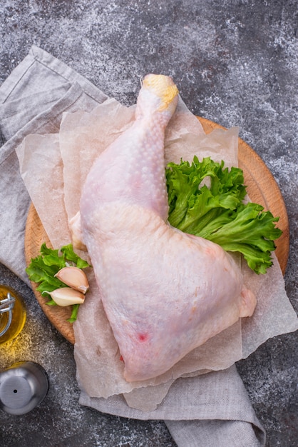 Cuisse de poulet cru sur planche à découper