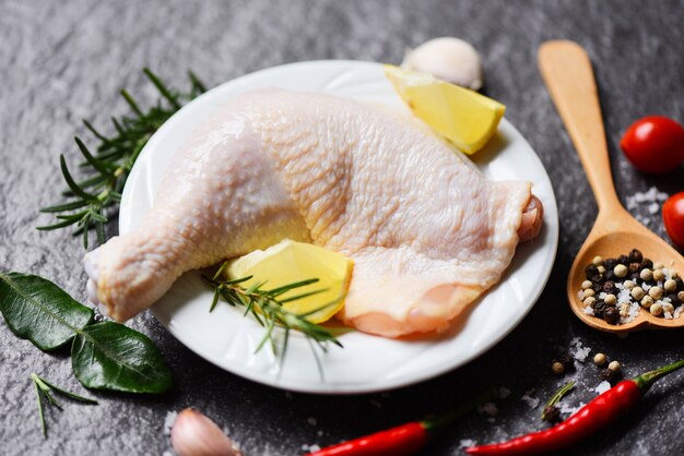 Cuisse de poulet cru sur plaque blanche pour la cuisson des aliments poulet au romarin citron sur table alimentaire