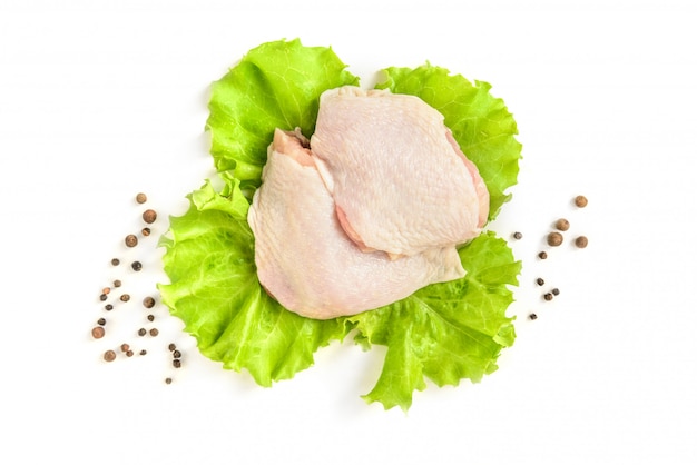 Cuisse de poulet cru et salade verte isolée sur fond blanc.