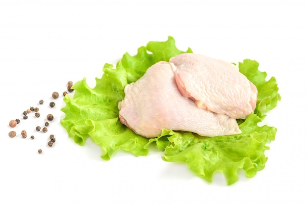 Cuisse de poulet cru et salade verte isolée sur fond blanc.