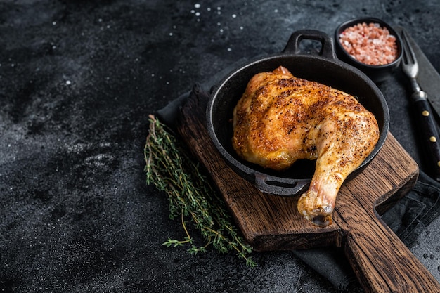 Cuisse de poulet frite au barbecue dans une poêle. Fond noir. Vue de dessus. Espace de copie.