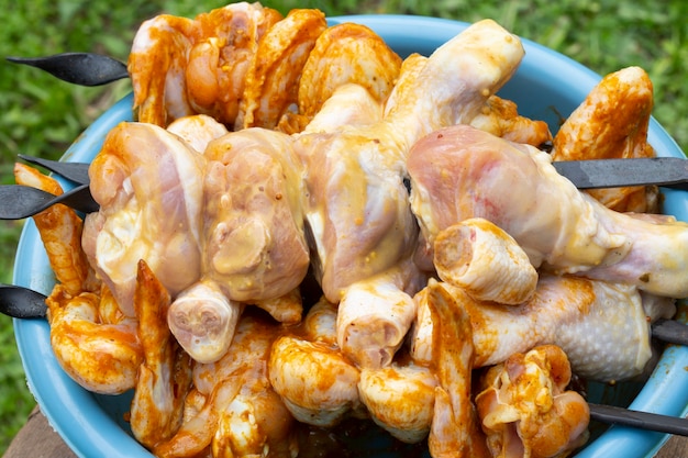 Cuisses et ailes de poulet marinées dans un bol sur des brochettes Pour la cuisson au tandoor ou les grillades