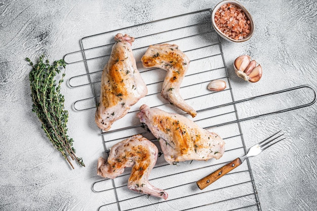 Cuisses de lapin au four sur un grill au thym. Fond blanc. Vue de dessus.