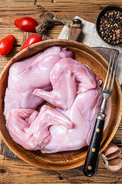 Cuisses de lapin crues dans une assiette en bois Fond en bois Vue de dessus