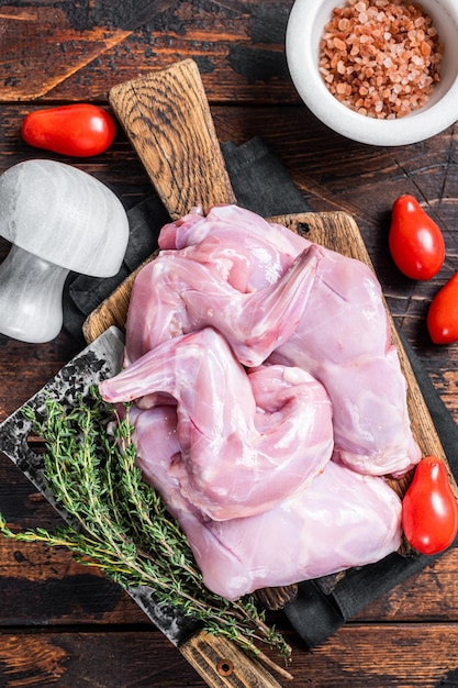 Cuisses de lièvre crues sur une planche de boucher au thym. Fond en bois sombre. Vue de dessus.