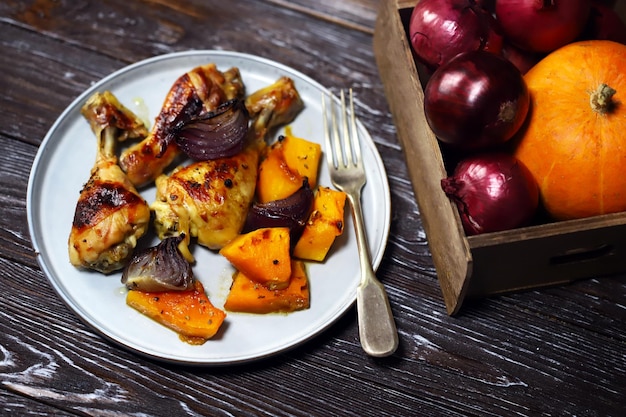 Cuisses de poulet au four avec citrouille et oignon bleu sur une assiette