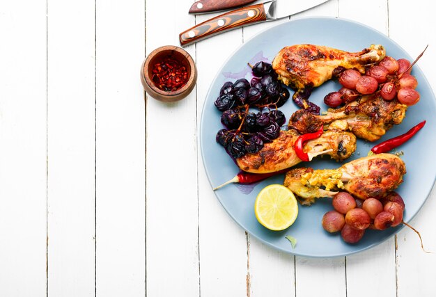 Cuisses de poulet au four avec des raisins sur fond de bois blanc