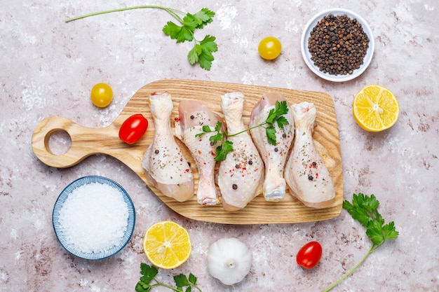 Cuisses de poulet aux épices et sel prêts à cuire sur une planche à découper.