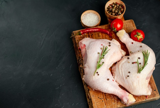 Cuisses de poulet cru aux épices et herbes prêtes à cuire sur un fond de pierre. avec espace de copie pour votre texte