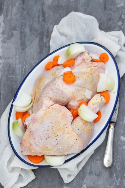 Photo cuisses de poulet cru avec carottes et oignons sur plat