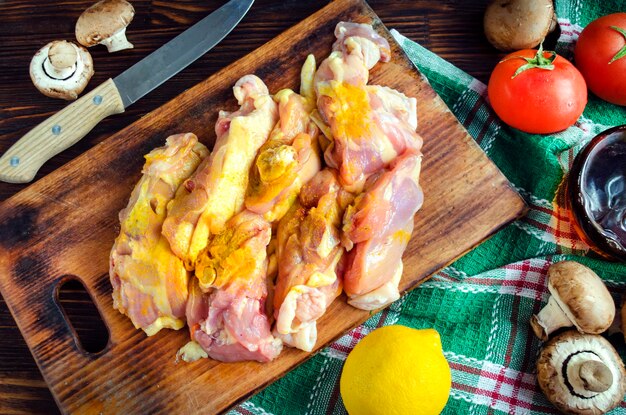 Photo cuisses de poulet crues aux épices, champignons et légumes