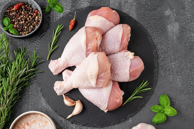 Cuisses de poulet crues non cuites sur une ardoise foncée sur fond de béton foncé Vue de dessus