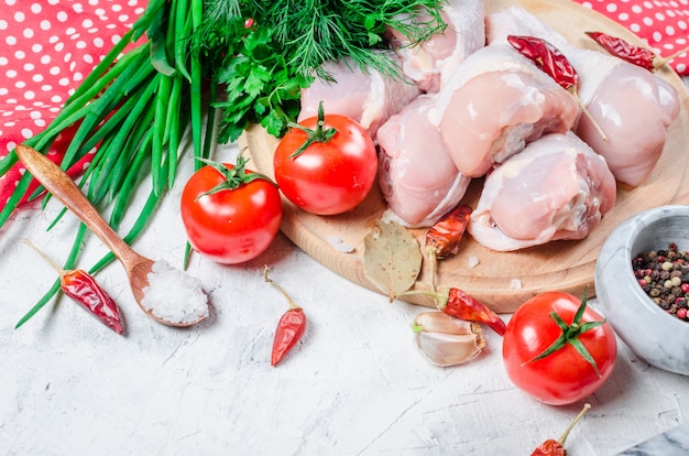 Cuisses de poulet crues sur une planche à découper avec des épices et des herbes.