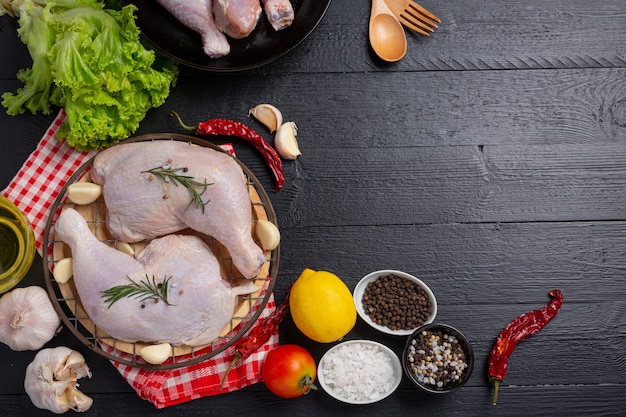 Cuisses de poulet crues sur la surface en bois sombre.